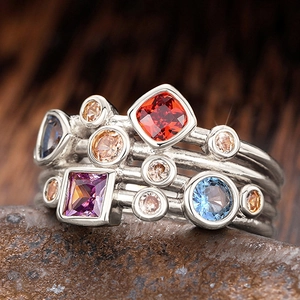 Primer plano de anillos de plata multicapa con piedras preciosas rojas, azules y púrpuras