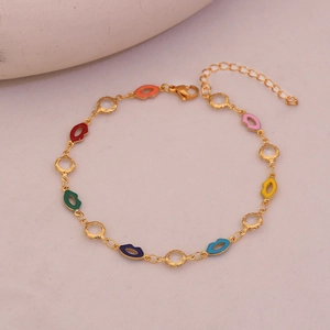 Close-up of golden anklet featuring colorful enamel lip charms and sparkling gemstones