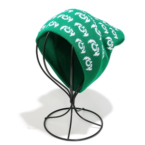 Detail of green knitted beanie showing white abstract jacquard pattern and ribbed edge