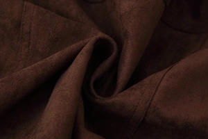 Dettaglio macro della texture scamosciata marrone scuro con finitura opaca morbida sulla giacca