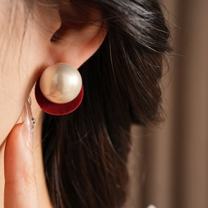 Detailed view of vintage French pearl earrings with red velvet circle on model's ear