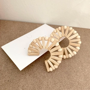 Detail of bohemian fan-shaped earrings made of natural wood beads and textured strips