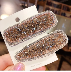 Detail of crystal hair clips in gold and brown showing rectangle and teardrop shapes