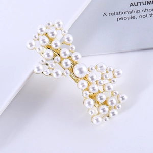 Macro shot of gold metal hair clip featuring white pearls in a delicate bow design