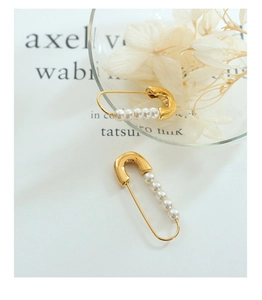 Detailed view of a gold safety pin brooch decorated with elegant white pearls on a clean background