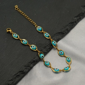 Detail of gold evil eye bracelet with blue beads and lobster clasp on textured stone
