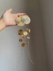 Detailed close-up of oversized gold geometric layered round fringe earrings