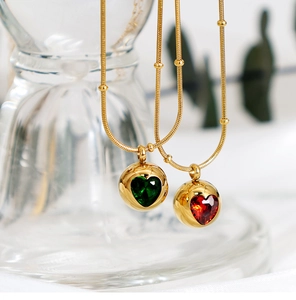 Détail macro de pendentifs cœur en émeraude et rubis sur chaîne serpent dorée