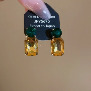 Detail of 925 silver stud earrings with emerald green and amber gemstone insets