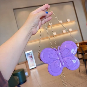 Détail d'un sac papillon violet pour fille avec une finition brillante et chaîne dorée