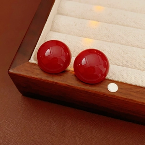 Dettaglio di orecchini rossi lucidi posti in un'elegante scatola porta gioielli in legno