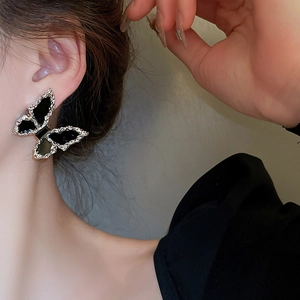 Close-up of silver butterfly earrings with black enamel inlay on model's ear