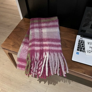 Detail of pink and green plaid scarf with long fringe on a wooden bench