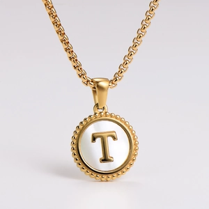 Macro shot of gold stainless steel necklace with round shell pendant and letter T design