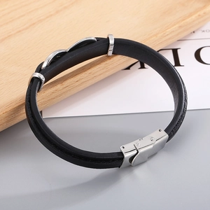 Detail of black woven leather bracelet with silver stainless steel clasp on wood tray