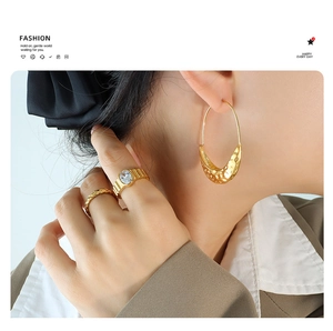 Detail showing hammered golden crescent earrings and statement rings on a model