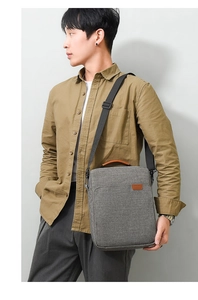 Man wearing gray oxford fabric messenger bag with brown handles in a side profile view