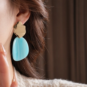 Vue détaillée d'une boucle d'oreille irrégulière en résine bleue et métal doré sur mannequin