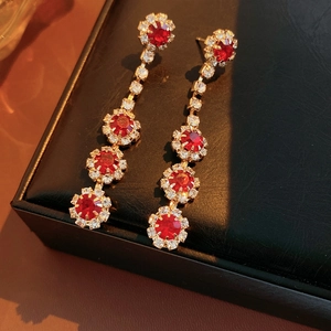 Macro view of gold flower earrings with red gemstones and white cubic zirconia details