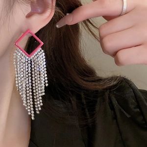 Macro side view of elegant rose pink diamond tassel earrings on a female model