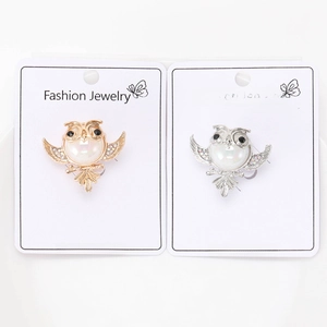Close-up of owl pins with iridescent pearls and rhinestones in gold and silver