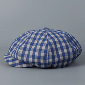 Close-up of the fabric texture and button detail on a blue-grey plaid newsboy cap