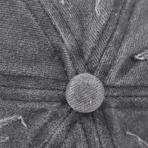 Macro shot of dark grey washed cotton baseball cap top button and stitched seam details