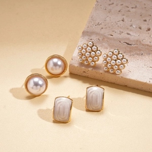 Detail of three pearl stud earrings sets featuring round, flower, and rectangle shapes