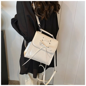 Detail of cream PU leather backpack featuring cross-lace design and bow decoration