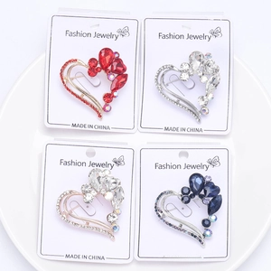 Collection of crystal heart brooches in red, blue, and silver on white display tray