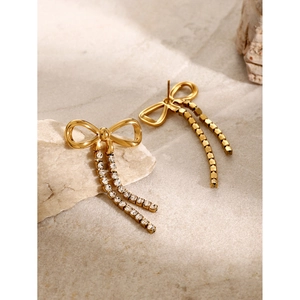 Elegant 18k gold plated bow earrings with sparkling rhinestone tassels on stone surface