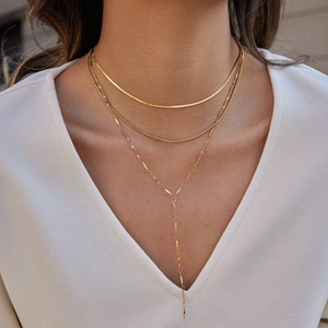 Close-up of gold layered triple necklace with flat snake chain and Y-shaped pendant design