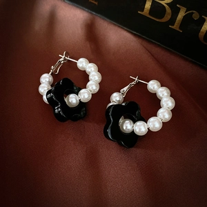Detailed close-up of vintage flower hoop earrings with white pearls on red silk