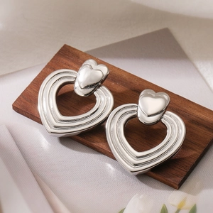Orecchini a doppia spirale a cuore in argento da donna su un blocco di legno naturale