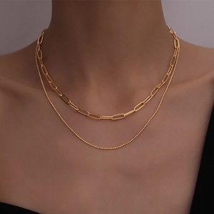 Close-up of layered 18k gold plated Cuban chain and bead necklace set on a model neck