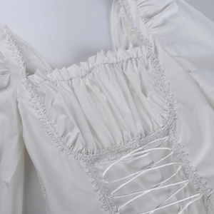 Detalle del vestido blanco de encaje con cordón en el pecho y adornos de volantes