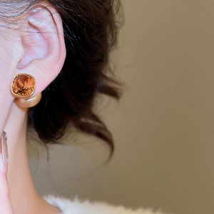 Detailed close-up of 18K gold plated amber crystal stud earrings with gold bead backing