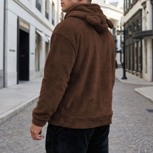 Detail of dark brown plush hoodie featuring animal ears on hood and faux fur texture