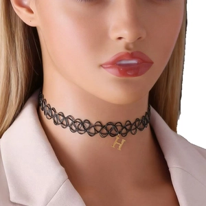 Detailed shot of a black braided tattoo choker with a small golden letter H pendant charm