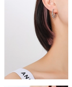 Close-up of a silver beaded hoop earring on a model's ear showing polished metal texture