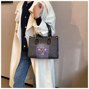Detail of a black tote bag with purple skull print and gold hardware worn by a model