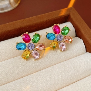 Close-up of golden floral stud earrings with multi-colored rhinestones in a jewelry box