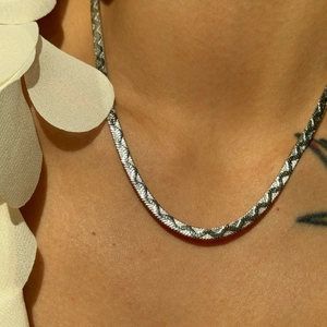 Gros plan d'une chaîne à chevrons plate en argent sur un modèle pour un look chic