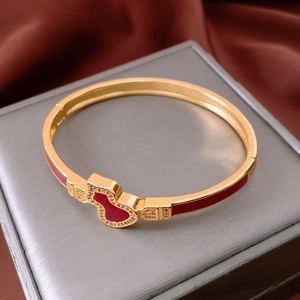 Macro detail of 18k gold plated gourd clasp bracelet with red enamel and white crystals