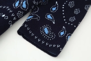 Macro view of navy blue knit cardigan featuring detailed light blue paisley patterns