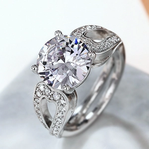 Bague argentée avec zircon rond et détails de cœur évidé sur la structure à quatre griffes