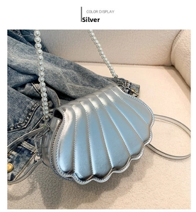 Details einer silbernen Muscheltasche mit Perlengriff und gesteppter Hochglanz-Optik