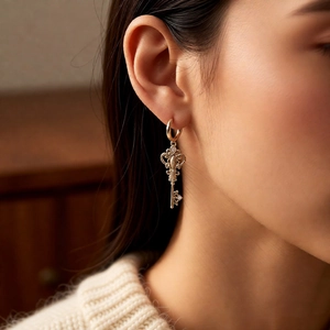 Close-up of vintage gold key earrings with zircon detailing worn by a model