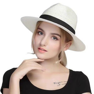 Close-up of white breathable straw sun hat with black ribbon detail worn by model