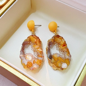 Detailed close-up of resin irregular earrings with orange and white stone fragments
